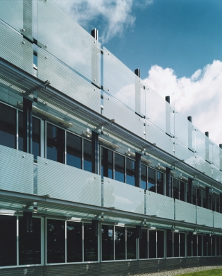 Exterior view of a two-story building with office windows and frosted glass.