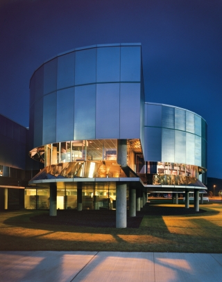 Exterior view of a building with gray panels on the top and clear windows on the middle and bottom of the building.